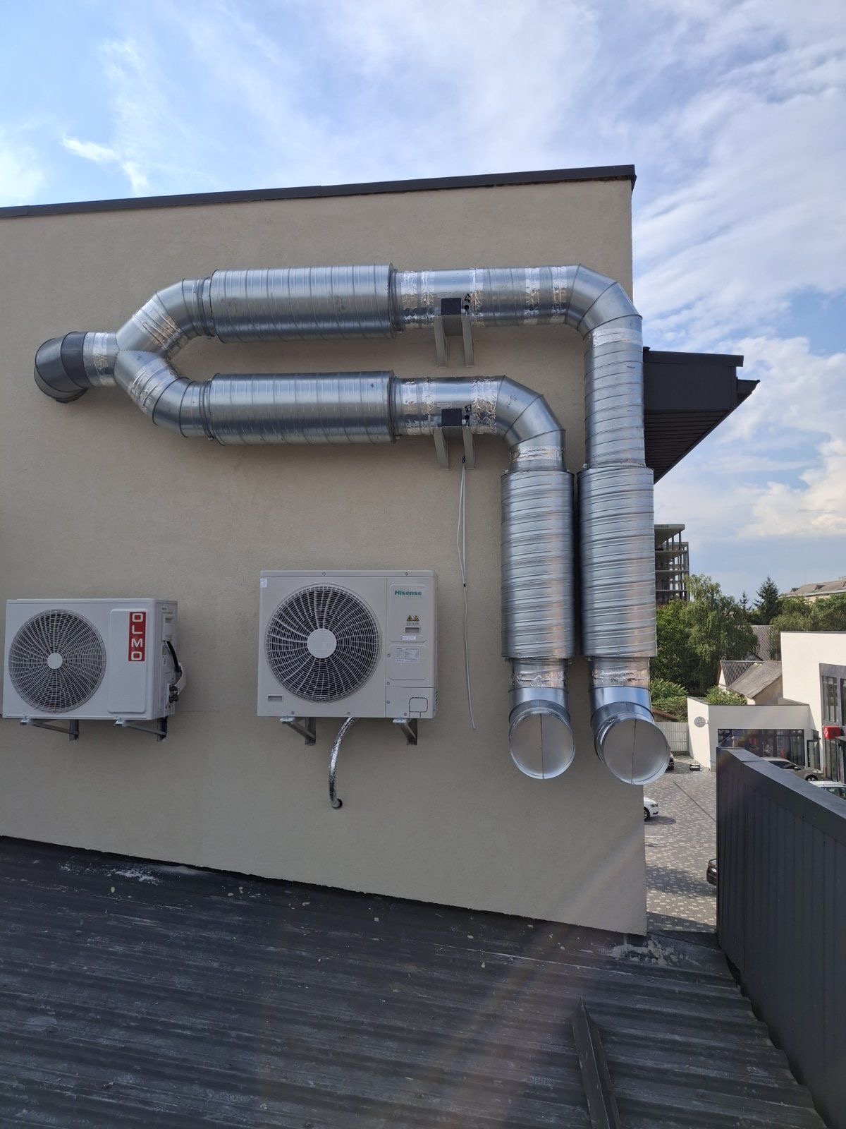 Wall-mounted condensers alongside galvanised spiral ducting on a building exterior.